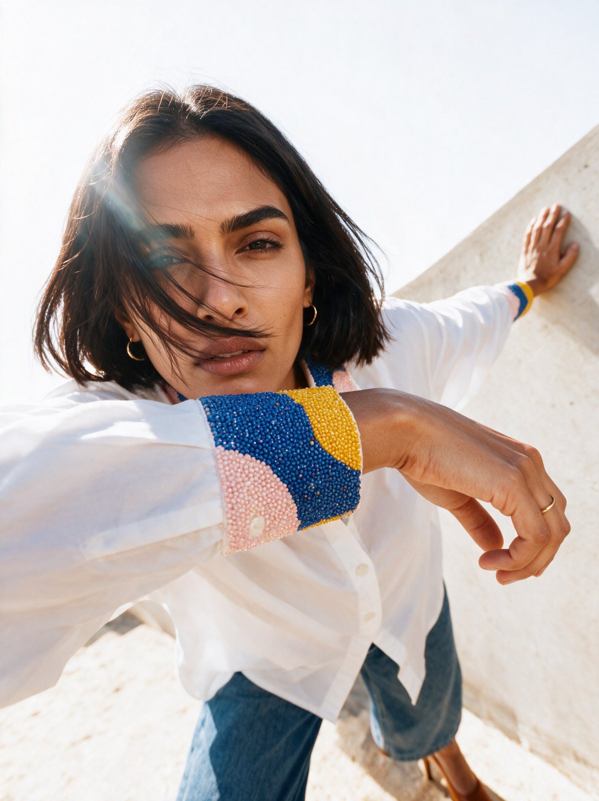 Model in a white shirt with a beaded cuff, hair in motion