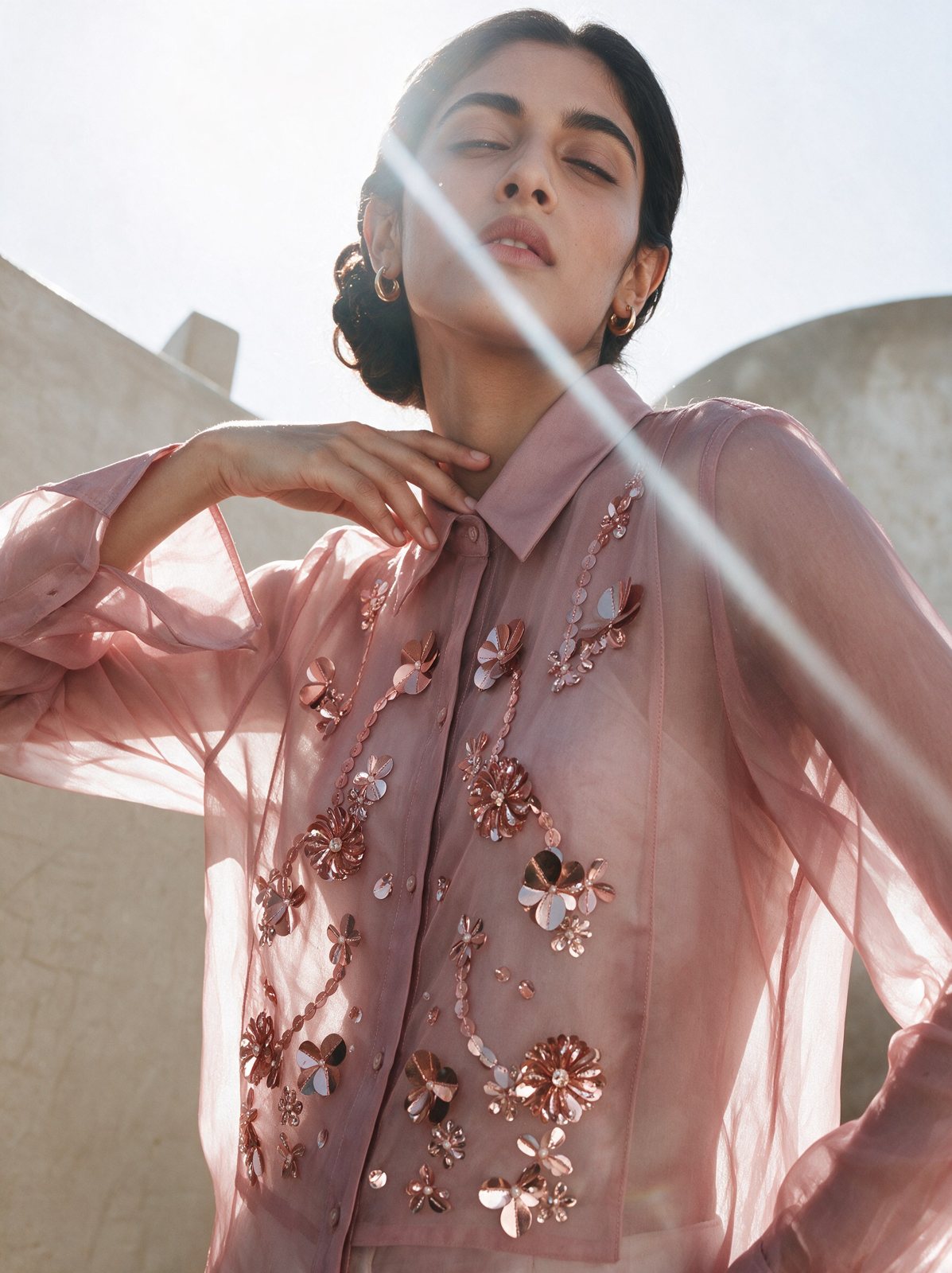 Model in a pink organza shirt with floral appliqué and sun flare