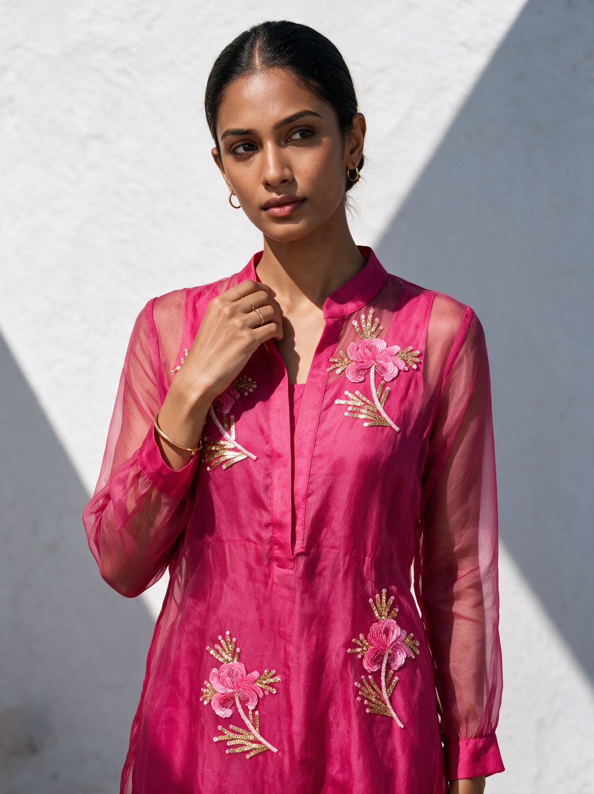 Model in a pink organza kurta with floral embroidery against a white wall