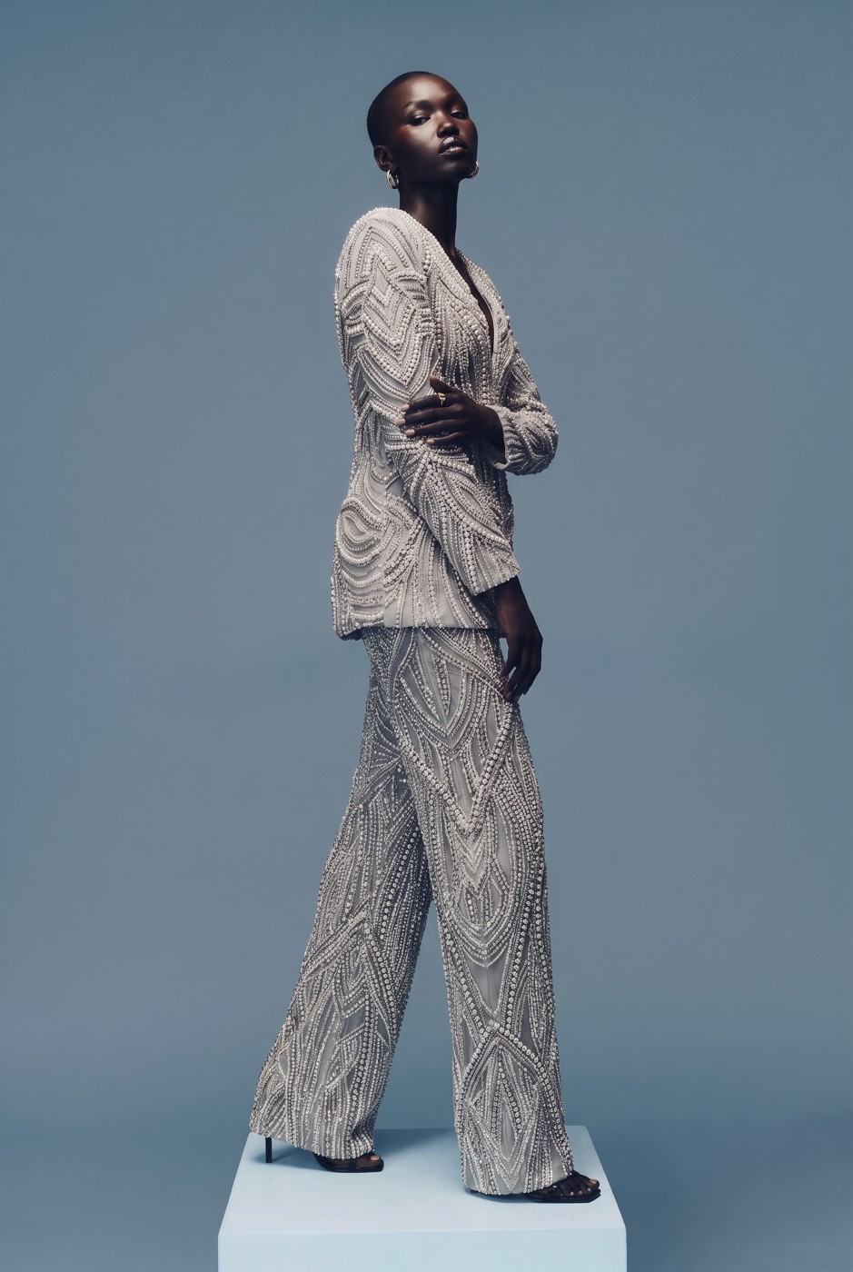 Model in a pearl-beaded trouser suit mid-stride