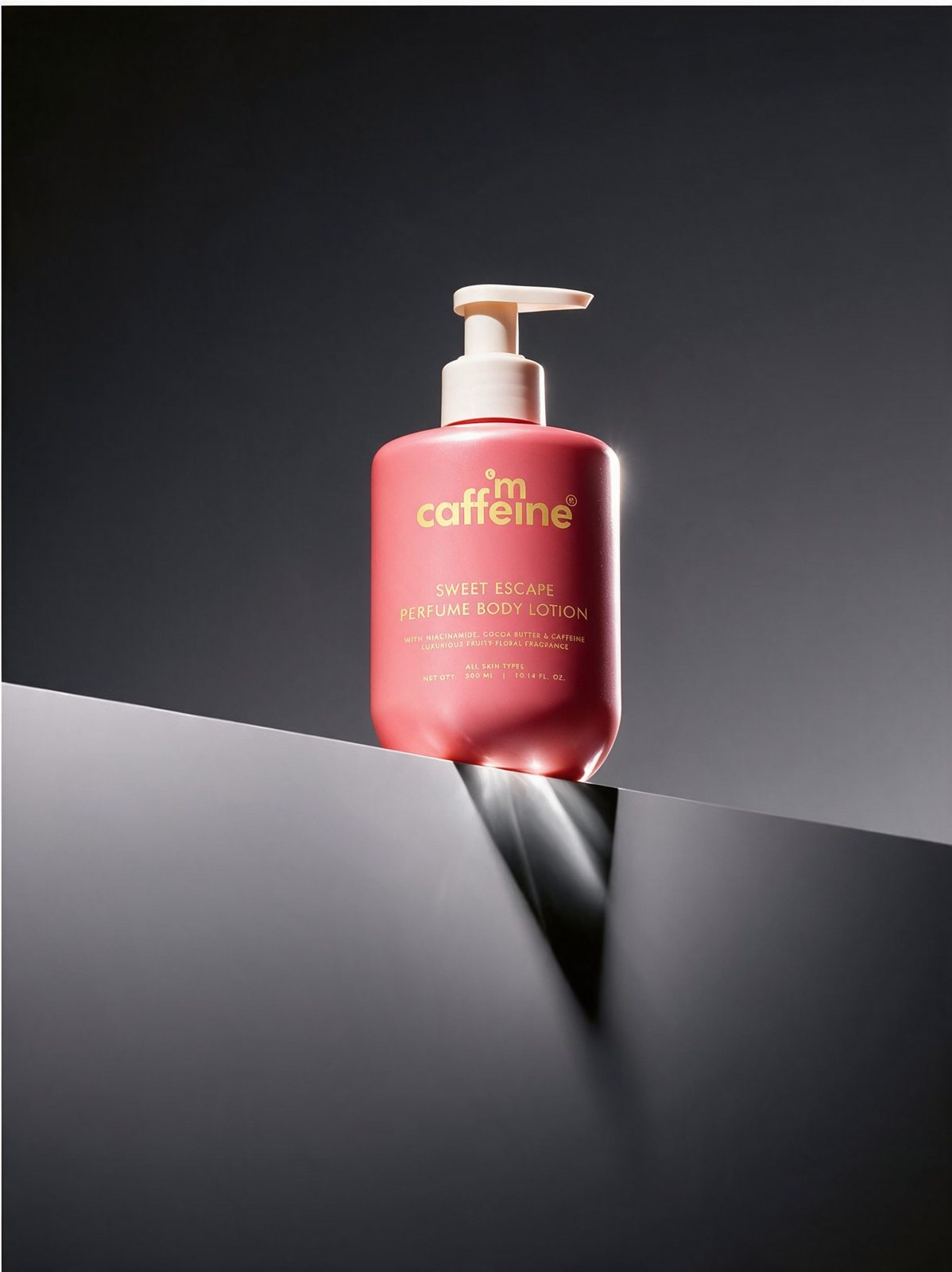A pink body lotion bottle on a dark ledge with a hard beam of light